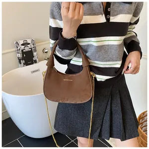 Vue détaillée d'un sac demi-lune en daim marron avec chaîne dorée et détails métalliques
