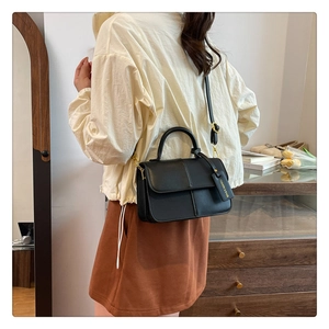 Détail d'un sac à main élégant en cuir noir avec poignée supérieure et bandoulière en chaîne