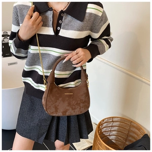 Détail d'un sac demi-lune marron vintage avec chaîne dorée et poignée sur un mannequin