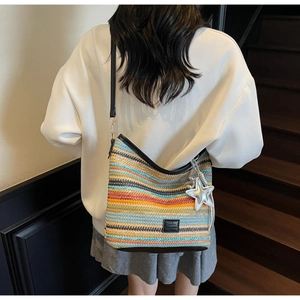 Detalle de bolso hobo tejido de rayas coloridas con colgante de estrella en modelo