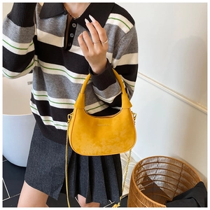 Détail du sac hobo jaune avec texture cuir mat et bandoulière chaîne dorée sur mannequin