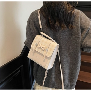 Detail view of cream checkered mini backpack with bow decoration worn by model