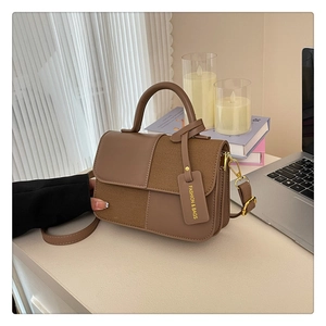 Détail d'un sac bandoulière en cuir et toile marron sur un bureau moderne et élégant