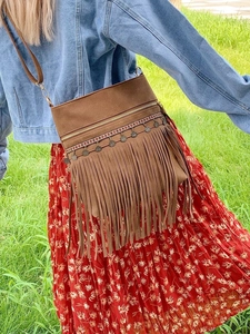 Sac bandoulière bohème en daim marron avec franges et motifs ethniques sur fond de nature