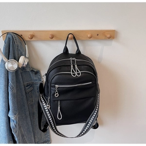 Detail of black pebbled leather backpack with silver zippers and woven shoulder strap