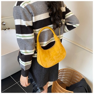 Détail du sac hobo jaune avec chaîne dorée porté sur un pull à rayures