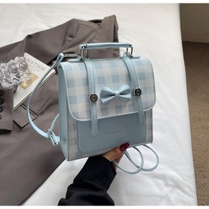 Detailed view of light blue checkered backpack with a bow and silver metal buckle