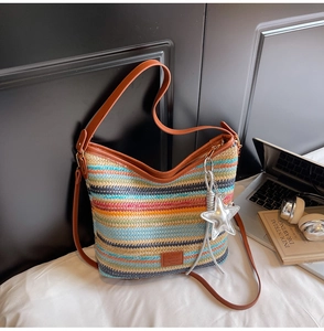 Detalle de bolso tipo cubo de paja tejida de colores con correa de cuero sintético