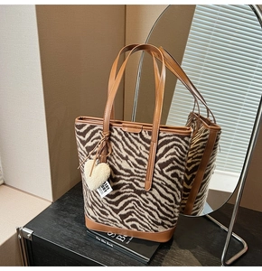 Detail of zebra pattern tote bag with leather straps and heart-shaped plush keychain charm