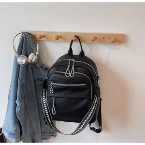 Detail view of black lychee leather backpack with geometric pattern woven shoulder strap