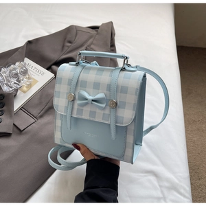 Detail of light blue checkered handbag with elegant bow decoration and metal buckle