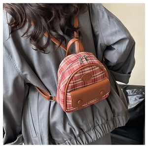Detail eines Mini-Rucksacks mit Karomuster und Lederriemen aus einer stilvollen Seitenansicht