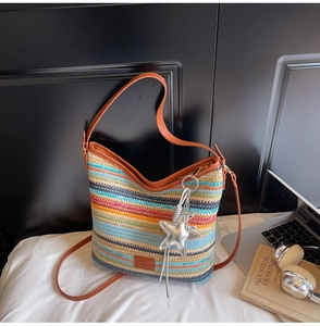 Detalle de bolso saco tejido a rayas coloridas con correa de cuero y colgante estrella
