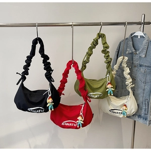 Row of colorful nylon pleated underarm bags with cute doll charms on metal hangers