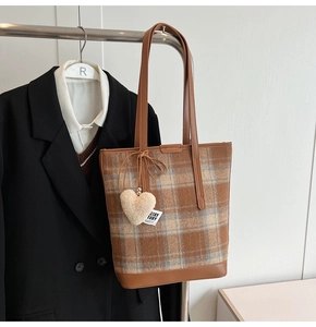 Détail du sac cabas à carreaux avec bandoulière en cuir brun et breloque cœur en peluche