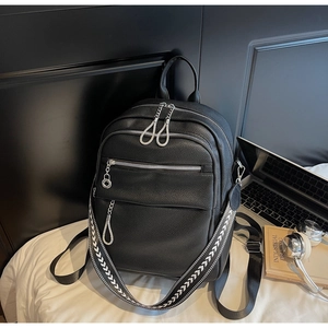 Close-up of black litchi pattern backpack with silver zippers and geometric strap