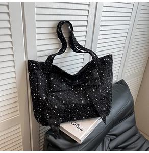 Detail of black canvas tote bag with white star pattern and large decorative bow