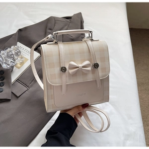 Detail of cream plaid backpack with decorative 3D bow and silver magnetic buckle clasp