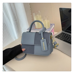 Détail du sac bandoulière en patchwork de cuir bleu et denim gris avec finitions dorées