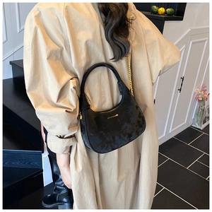 Détail du sac lune noir à texture tie-dye avec chaîne dorée porté par un mannequin
