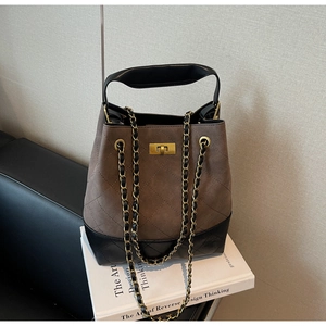 Detail of quilted brown suede bucket bag featuring contrast black base and gold twist lock