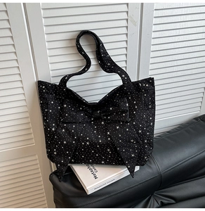 Close-up of black nylon tote bag with white star patterns and large decorative bow detail