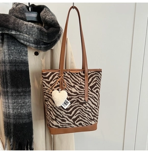 Détail de la texture en peluche zébrée et du pendentif cœur sur un sac en cuir