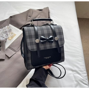 Detail of grey plaid and black leather backpack with a bow knot and silver buttons