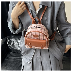 Detail view of mini pink plaid backpack with brown leather trim worn by a model