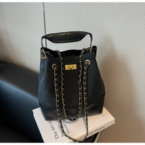 Detail of black quilted leather bucket bag featuring gold metal swivel lock and chain straps