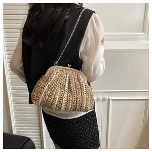 Détail du sac en paille tressée en forme de coquille avec bandoulière dorée sur un mannequin
