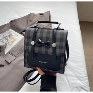 Detail of checkered leather backpack featuring a black bow and metallic buckles in style