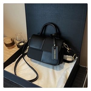 Détail du sac bandoulière noir avec textures de cuir mixtes et pendentif doré
