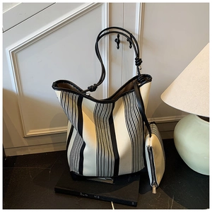 Detail of striped canvas tote bag with thick black rope handle and mini clutch