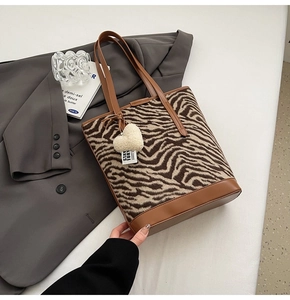 Détail d'un sac seau à motif zèbre avec poignée marron et charme de cœur en peluche