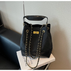 Close-up of quilted black bucket bag with gold chain strap and metal twist-lock detail