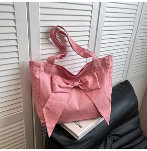 Detailed texture of pink canvas tote bag with silver star patterns and large bow