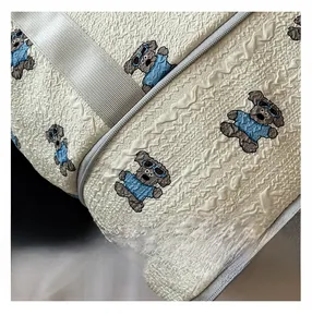 Close-up of white bubble texture fabric with cartoon bear pattern and gray zipper