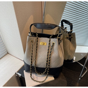 Detailed shot of two-tone quilted bucket bag with chain strap and gold hardware accents