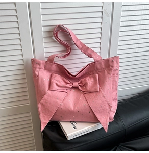 Detailed close-up of pink canvas tote bag featuring silver star prints and a large bow design
