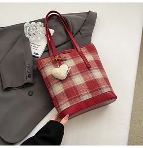 Détail du sac seau en tweed à carreaux rouges avec breloque cœur en fausse fourrure