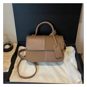 Détail du sac à main marron en toile et cuir dans une boîte cadeau avec étiquette