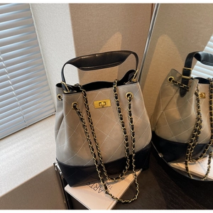 Detail of the diamond quilted texture and golden twist-lock closure on the bucket bag