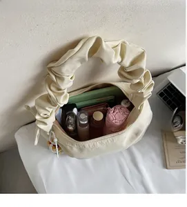 Interior view of cream pleated dumpling bag showing storage space for phone and wallet