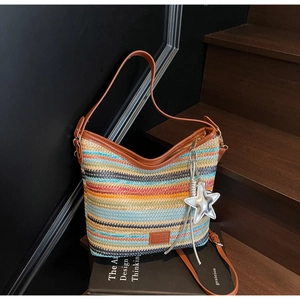 Detalle de bolso saco de tejido multicolor con ribete de cuero marrón y dije de estrella