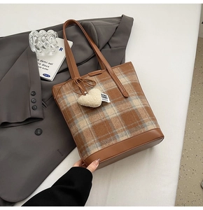 Détail d'un sac cabas à carreaux avec bordure en cuir marron et pendentif cœur