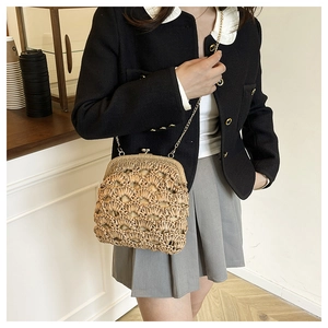 Détail du sac en paille tressée avec forme de coquillage et bandoulière dorée
