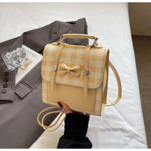 Detail of yellow and white plaid patchwork handbag featuring a 3D decorative bow accent