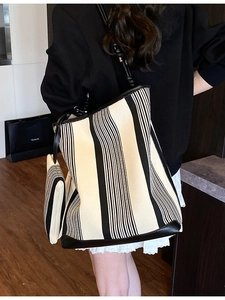 Minimalist black and white striped canvas tote bag with leather handles shown on model