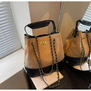 Detailed view of khaki suede and black leather bucket bag with gold chain and turn-lock